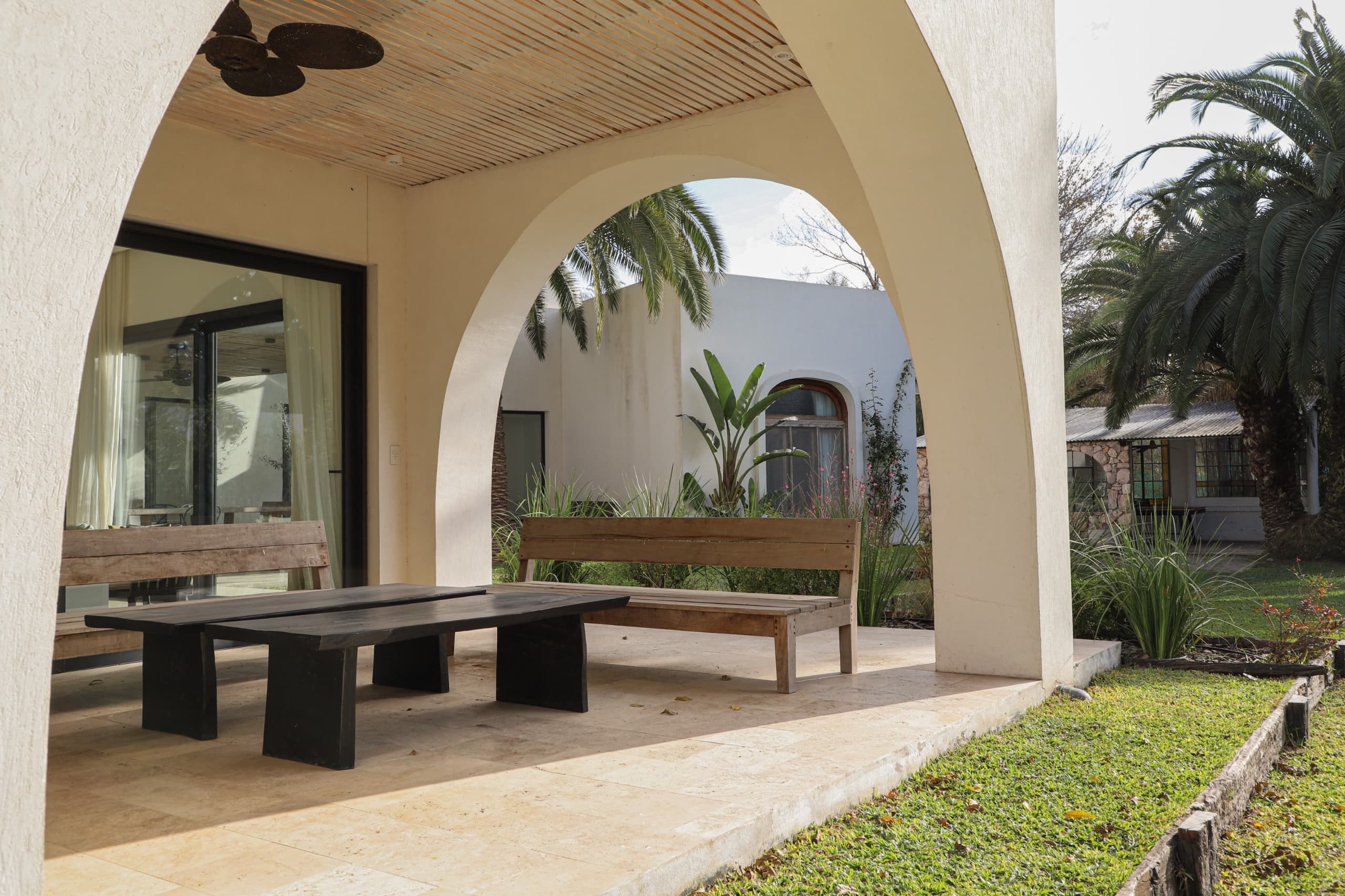 Galería cubierta con mesa de madera y vista al jardín